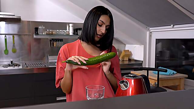 A cute girl peels a cucumber for her older man in a sensual scene.
